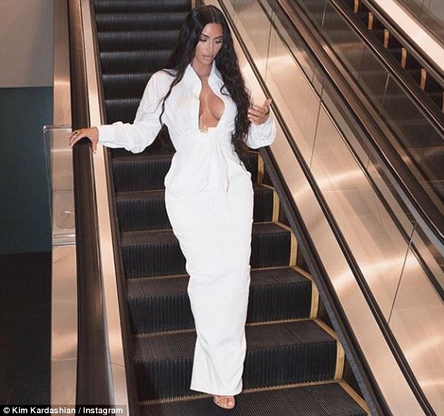 Kim Kardashian flashes her cleavage in plunging white Dress as she gazes at imaginary cellphone